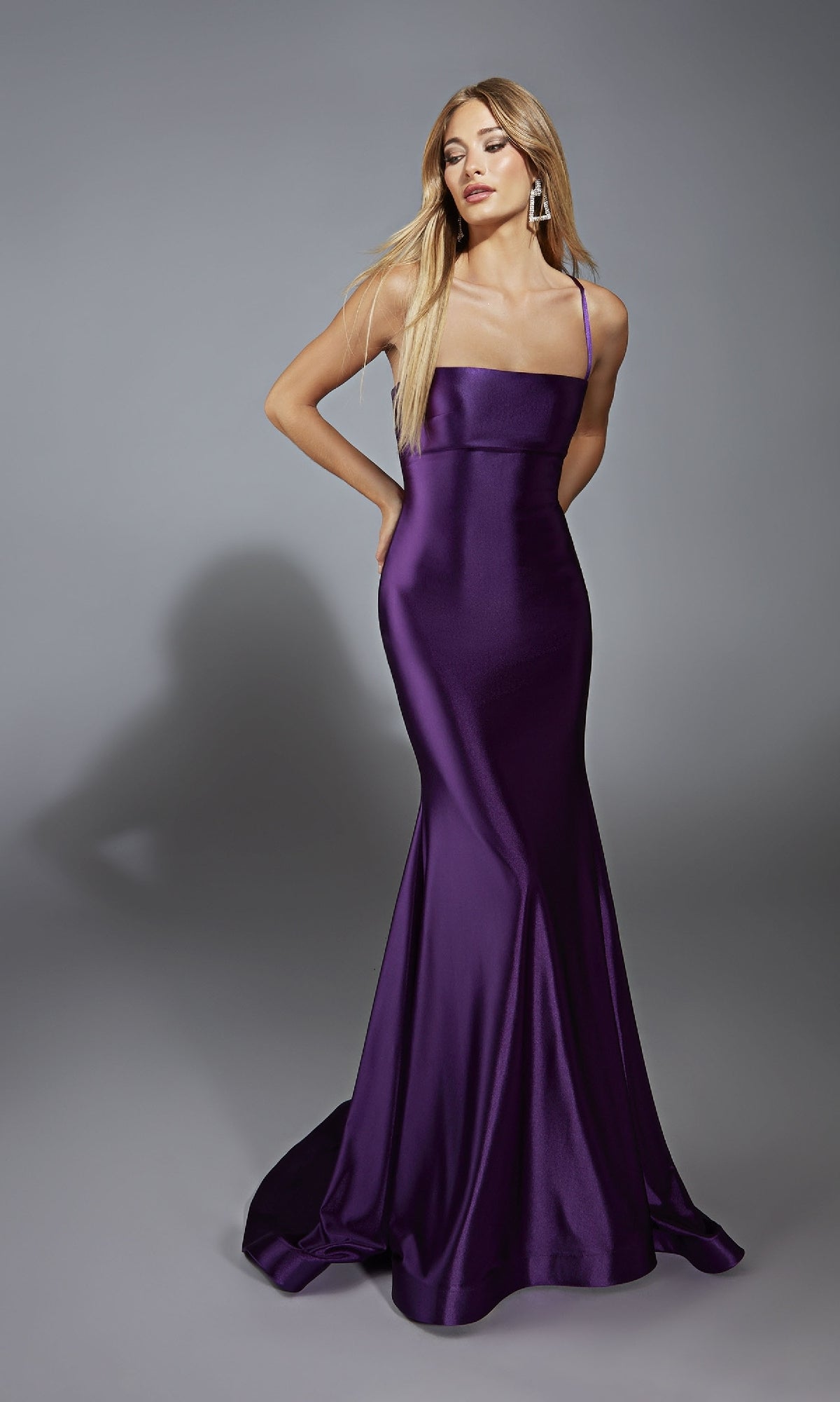 Wearing the Lace-Up Open-Back Long Prom Dress: Aerie Couture 313, a woman poses against a gray backdrop in a fitted, floor-length purple satin gown with thin straps and an elegant open-back design.